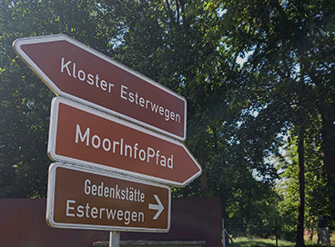 Das Symbolbild zeigt eine Hinweistafel, die zur Gedenkstätte führt.